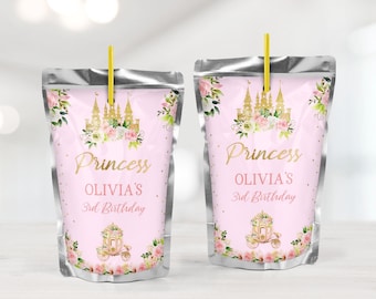 Könnte beinhalten: Zwei rosa Saftbeutel mit goldenem Text, der "Prinzessin OLIVIA'S 3. Geburtstag" lautet. Jeder Beutel zeigt ein goldenes Schloss, eine Kutsche und florale Akzente. Ein gelber Strohhalm ist oben eingesetzt.