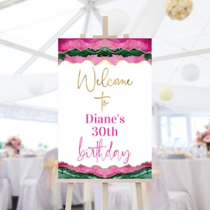 May include: Welcome to Diane's 30th birthday sign with a pink and green agate design. The sign is on a wooden easel.