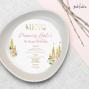 Peut inclure: Une assiette ronde blanche avec un motif de château rose et or. L'assiette présente un menu pour le 4ème anniversaire royal de la princesse Halo. Le menu comprend des entrées, des plats principaux et des desserts.