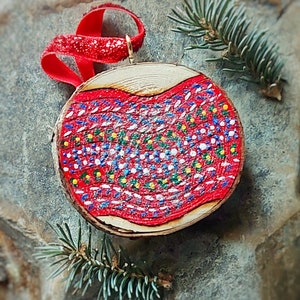 Peut inclure: Une décoration de Noël en bois peinte en rouge, blanc et bleu avec un ruban rouge. La décoration est ornée d'un motif de pois.