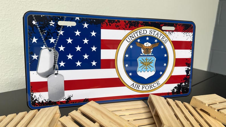 May include: A blue and red American flag with a distressed look. The flag has a white star field and red and white stripes. The flag has the United States Air Force seal in the centre. The seal is blue with a white eagle and the words "United States Air Force".