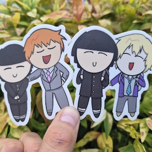 Puede incluir: Una pegatina troquelada con cuatro personajes de dibujos animados en dos parejas. La pareja de la izquierda muestra un personaje con uniforme negro y otro con pelo naranja en traje gris. La pareja de la derecha muestra un personaje con uniforme negro y otro con pelo rubio en chaqueta morada y corbata azul.