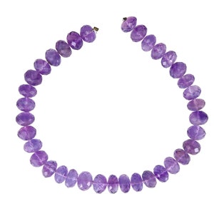 May include: A strand of purple amethyst beads, strung together to form a necklace. The beads are faceted and have a slightly oval shape.