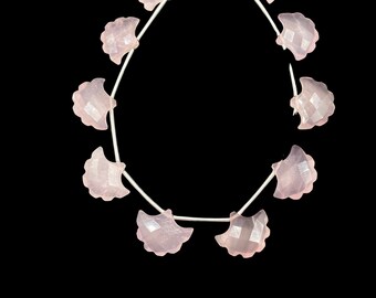 May include: A strand of pink rose quartz beads, each bead is carved in the shape of a scallop shell. The beads are strung on a silver chain.
