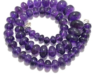 May include: A strand of purple amethyst gemstone beads, strung on a silver chain. The beads are oval-shaped and have a smooth, polished finish.