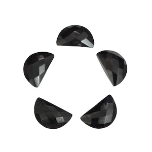 May include: Five black, half-moon shaped gemstones arranged in a circular pattern. Each gem has a faceted surface, catching the light and creating a sparkling effect. The gems are a deep, solid black color.