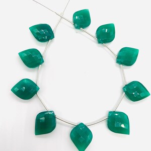 May include: A strand of 10 faceted green gemstone beads, each shaped like a teardrop, strung on a silver wire.