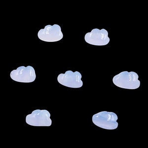 May include: Seven translucent, light blue, cloud-shaped stones on a black background.