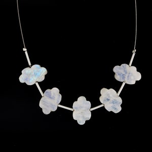 Peut inclure: Un collier en chaîne argent avec six perles en forme de nuage de pierre de lune irisée.