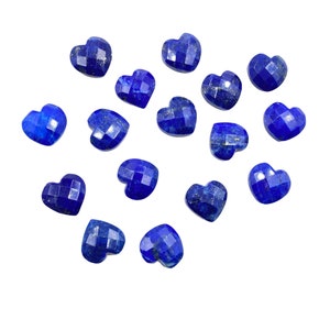 May include: A collection of 15 heart-shaped lapis lazuli gemstones. The stones are a deep blue color with flecks of gold.