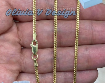 Könnte beinhalten: Eine goldene Kettenkette mit einem Karabinerverschluss. Die Kette ist im Curb-Stil und wird auf einer Hand gezeigt.