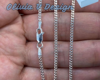 Könnte beinhalten: Eine silberne Curb-Kette mit einem Karabinerverschluss. Die Kette liegt auf einer Hand und zeigt die Länge und Breite der Kette.