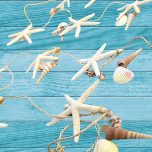 May include: A decorative garland featuring starfish and seashells strung on natural twine. The starfish are a creamy white color, and the seashells vary in shape and color. The background is a blue wooden surface.