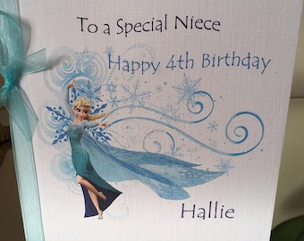 May include: A white greeting card with a light blue ribbon and bow. The card features the text "To a Special Niece Happy 4th Birthday Hallie" and an illustration of a character in a blue dress.
