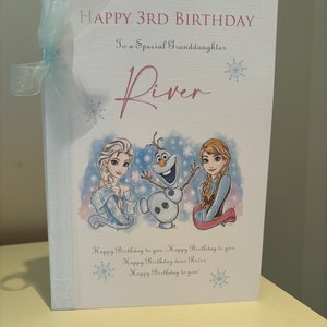 K&ouml;nnte beinhalten: Geburtstagskarte mit hellblauem Band. Auf der Karte steht "HAPPY 3RD BIRTHDAY" und "To a Special Granddaughter River". Sie zeigt Illustrationen von Elsa, Olaf und Anna aus Frozen. Auf der Unterseite der Karte steht "Happy Birthday to you!"