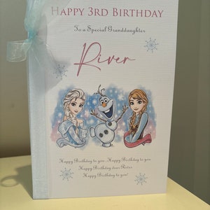 K&ouml;nnte beinhalten: Geburtstagskarte mit dem Text "HAPPY 3RD BIRTHDAY" und "To a Special Granddaughter River". Die Karte zeigt Illustrationen von Elsa, Olaf und Anna aus Frozen, mit einem hellblauen Band an der Seite.