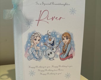 Könnte beinhalten: Geburtstagskarte mit dem Text "HAPPY 3RD BIRTHDAY" und "To a Special Granddaughter River". Die Karte zeigt Illustrationen von Elsa, Olaf und Anna aus Frozen, mit einem hellblauen Band an der Seite.