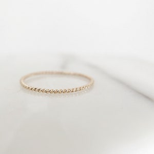 May include: A delicate gold ring with a twisted band.