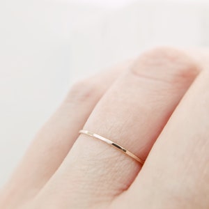 May include: A thin gold band ring worn on a finger.