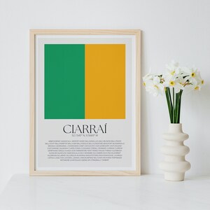 Puede incluir: Un estampado enmarcado con un diseño de bloques de color verde y dorado. La palabra "CIARRAÍ" está centrada en la parte inferior, con coordenadas y nombres de lugares debajo. Un jarrón de flores blancas está a la derecha.