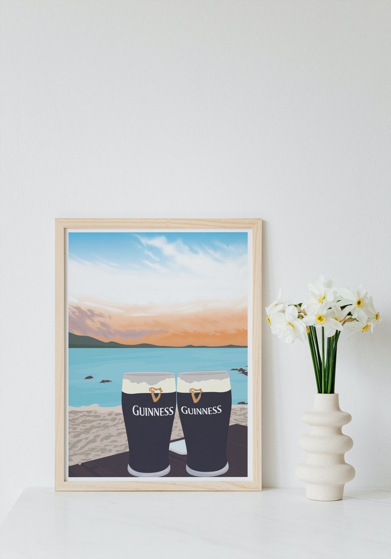 Pu&ograve; includere: Una stampa incorniciata di due bicchieri di birra Guinness su una spiaggia con un tramonto sullo sfondo.
