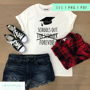 May include: White t-shirt with a black graduation cap and the text "Schools out for summer forever!" crossed out. The shirt is laid out on a wood surface with a pair of black sneakers, denim shorts, and a red and black plaid shirt.