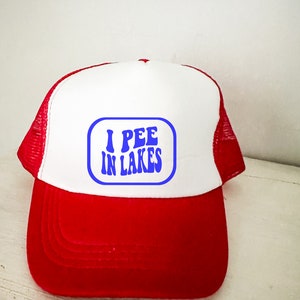 May include: A red and white trucker hat with a blue and white rectangular patch that says "I PEE IN LAKES" in a retro font.
