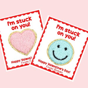 May include: Two Valentine's Day cards with the text "I'm stuck on you!" and a heart-shaped and a smiley face-shaped cookie. The heart-shaped cookie is pink and the smiley face cookie is blue. The text "Happy Valentine's Day!" is on the bottom of each card.