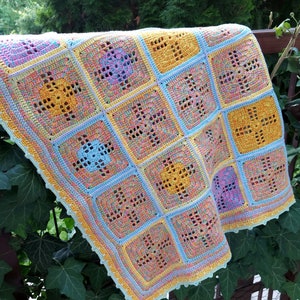 May include: A crocheted baby blanket with a colorful geometric pattern in shades of blue, yellow, and pink. The blanket is made with a variety of stitches and has a scalloped edge.