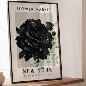 May include: A framed art print featuring a black rose with gold accents, part of the "Flower Market New York Botanical Print Collection." The artwork is displayed on a wooden ledge near a window, with neutral-toned decor.