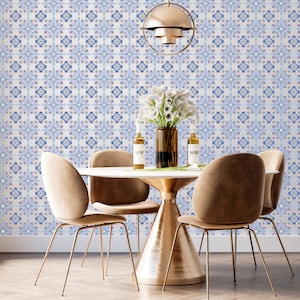 May include: A white dining table with a gold base and four brown chairs. The table is set with two clear glass bottles and a vase of white flowers. The wall behind the table is covered in a blue and white patterned wallpaper.