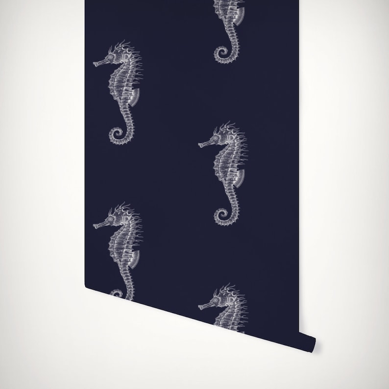 Peut inclure: Papier peint bleu marine avec un motif r&eacute;p&eacute;t&eacute; d'illustrations d'hippocampes blancs. Les hippocampes sont dessin&eacute;s avec pr&eacute;cision, cr&eacute;ant une ambiance classique et artistique. Le rouleau de papier peint r&eacute;v&egrave;le sa texture, &eacute;voquant un th&egrave;me nautique.