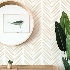 May include: A beige and white chevron patterned wallpaper with a round wooden mirror, a small potted succulent, and a green leafy plant in the corner.