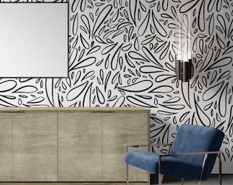 Op de afbeelding: Een modern interieur met een witte muur versierd met een zwart abstract patroon. Een groot, leeg wit canvas hangt boven een licht houten kast. Een blauwe fauteuil met een roségouden frame staat in de buurt. Een zwarte en heldere glazen wandlamp is aan de muur bevestigd.