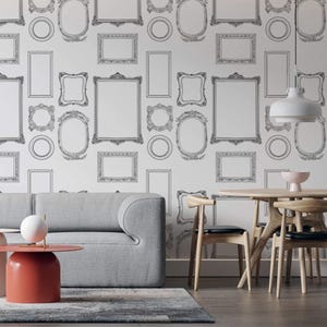 May include: A modern living room with a gray sofa, a red side table, and a wooden dining table. The wall is decorated with a wallpaper featuring a pattern of black and white ornate picture frames of various shapes and sizes.