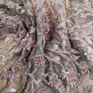 May include: Pink beaded lace fabric with a floral design. The fabric is sheer and delicate, with a soft, romantic feel.