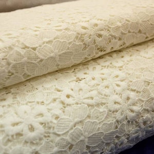 May include: White lace fabric with a delicate floral pattern. The lace is soft and lightweight, making it ideal for a variety of crafting projects.