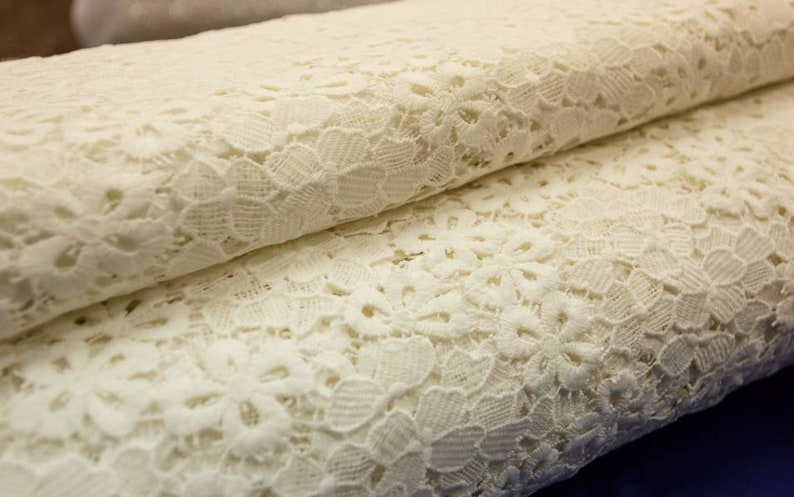 May include: White lace fabric with a delicate floral pattern. The lace is soft and lightweight, making it ideal for a variety of crafting projects.