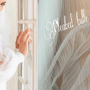 May include: A white dress with pleated tulle fabric sleeves. The fabric is sheer and has a delicate, flowing texture. The dress is a beautiful example of how tulle can be used to create a romantic and elegant look.