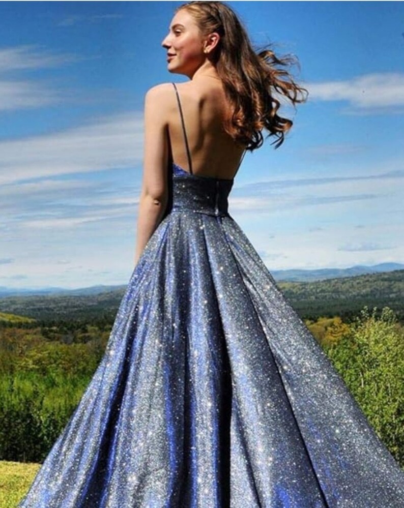 May include: A long, blue, sparkly, sleeveless dress with a V-neckline and a flowing skirt.