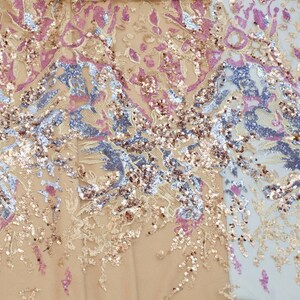 May include: A close-up of a fabric with a floral pattern and sequins in shades of pink, gold, and blue.