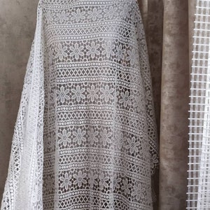 May include: White crochet fabric with a floral pattern. The fabric is delicate and has a soft texture.