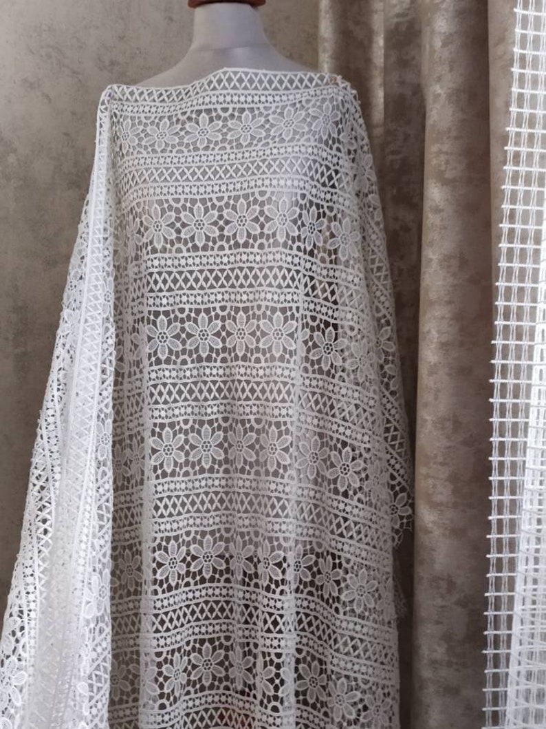 May include: White crochet fabric with a floral pattern. The fabric is delicate and has a soft texture.
