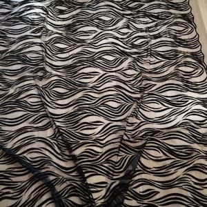 May include: Black and white wavy patterned fabric. The fabric has a sheer, mesh-like texture.