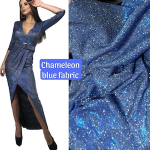May include: A blue sparkly fabric with a chameleon effect. The fabric is textured and has a subtle shimmer. The text "Chameleon blue fabric" is written on a white background.