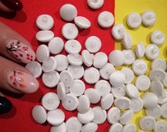 May include: A large pile of white buttons with a textured surface. The buttons are arranged in a random pattern on a red and yellow background.