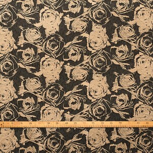 May include: Beige rose pattern on a dark brown fabric. The fabric is measured with a ruler in inches.