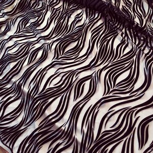 May include: Black and white fabric with a wavy zebra print pattern.