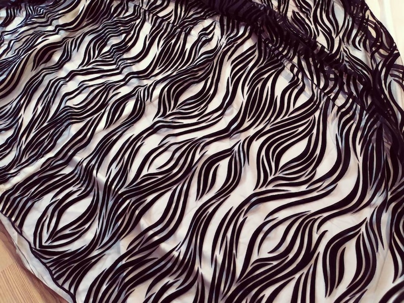 May include: Black and white fabric with a wavy zebra print pattern.