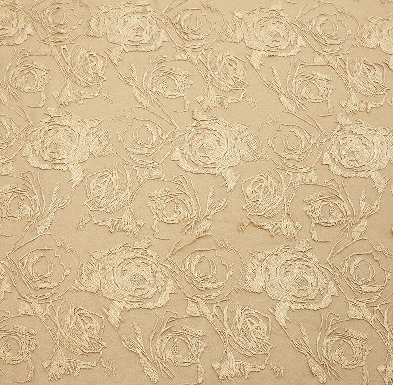 May include: A beige fabric with a raised embossed pattern of white roses. The fabric has a subtle sheen and a soft texture.